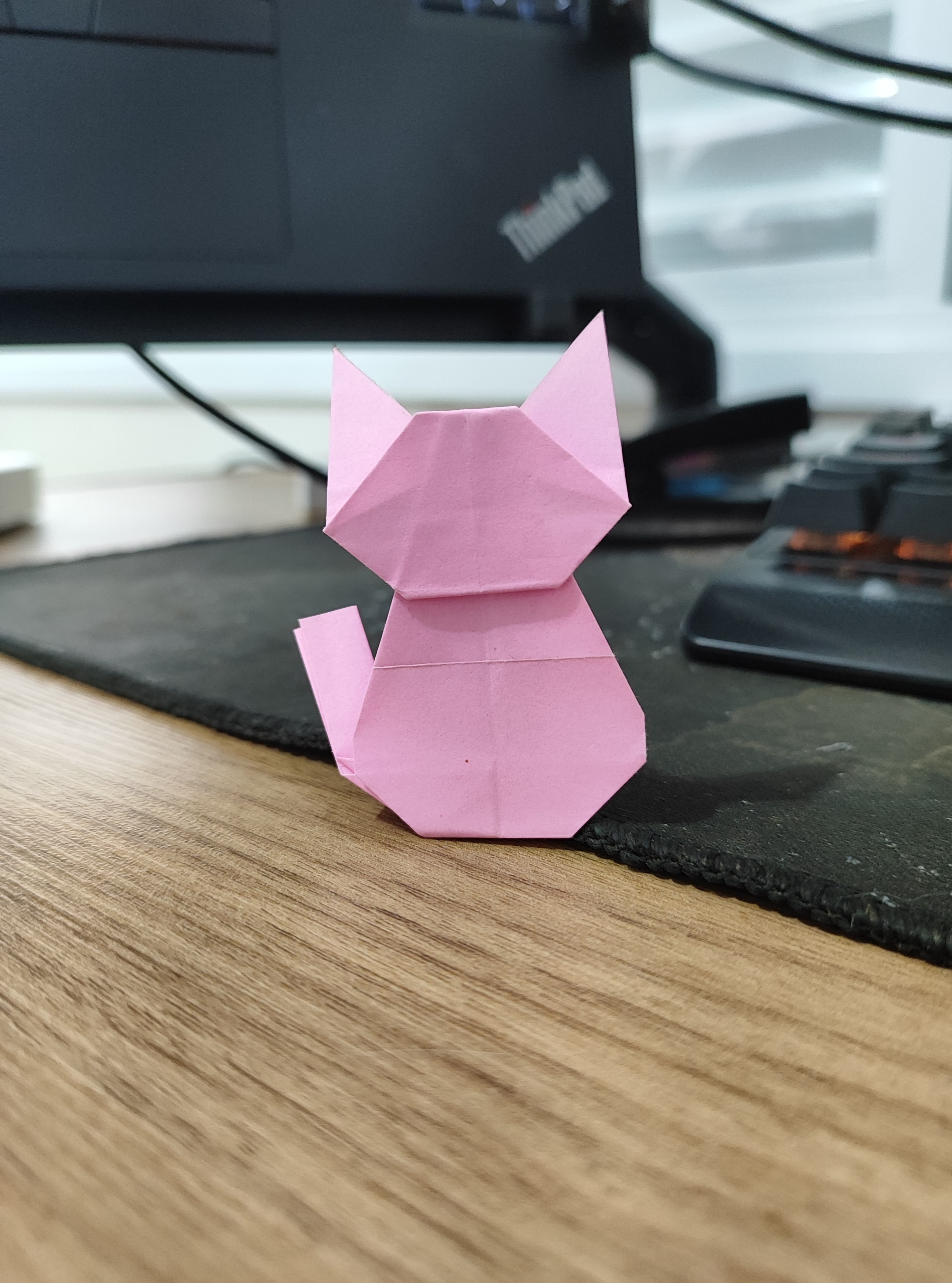 Pink sitting cat origami folded from a rectangular sheet