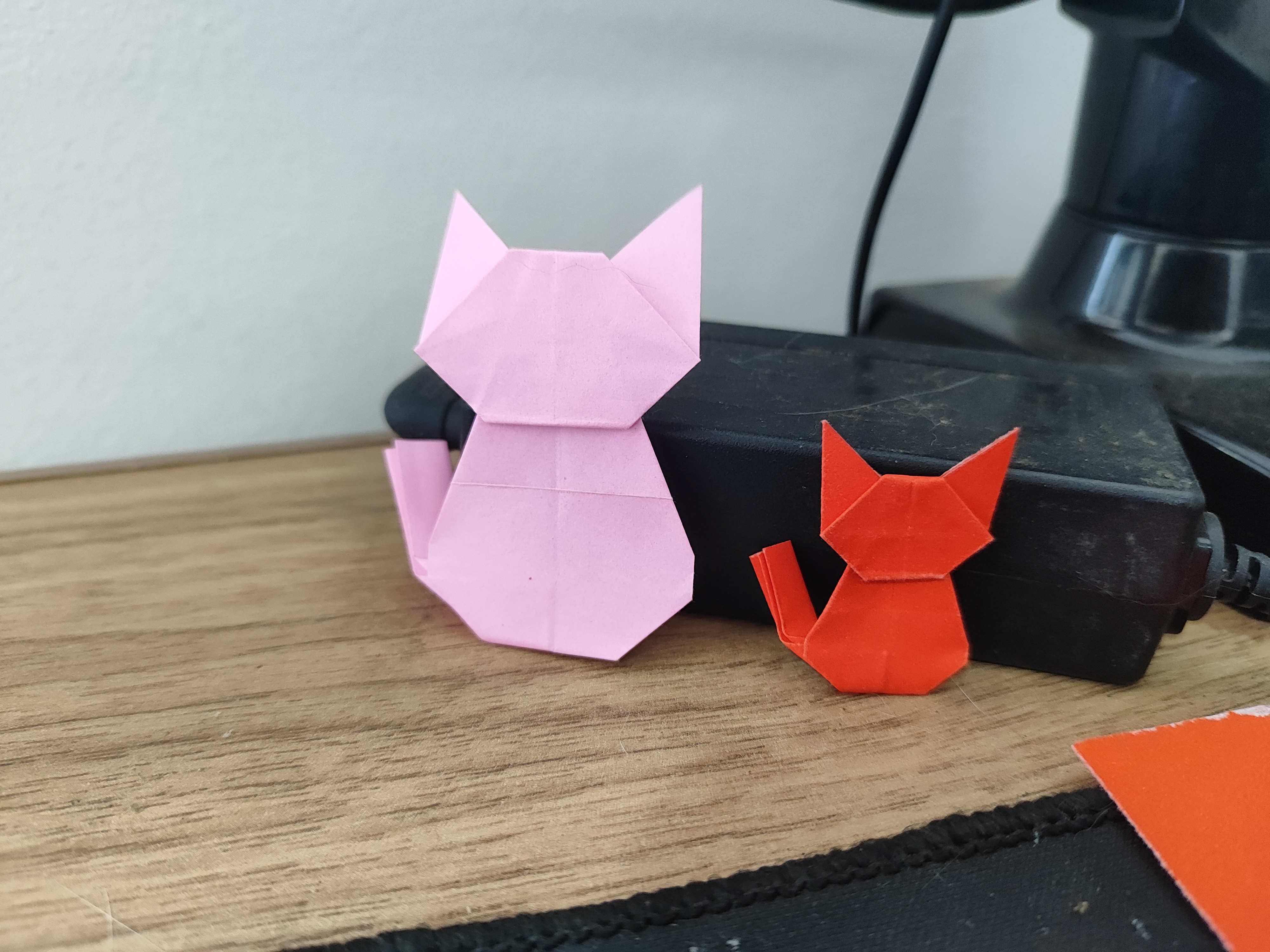 Pink and red sitting cat origami models folded in two different sizes